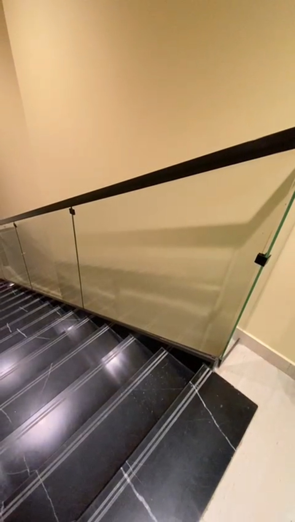 Frameless glass balustrade with dark bronze top handrail on a black marble staircase at the Ministry of Culture
