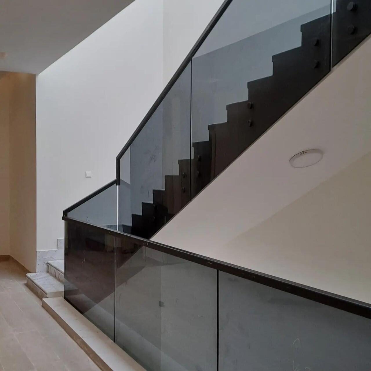 Black tinted glass stair railing with steel handrail