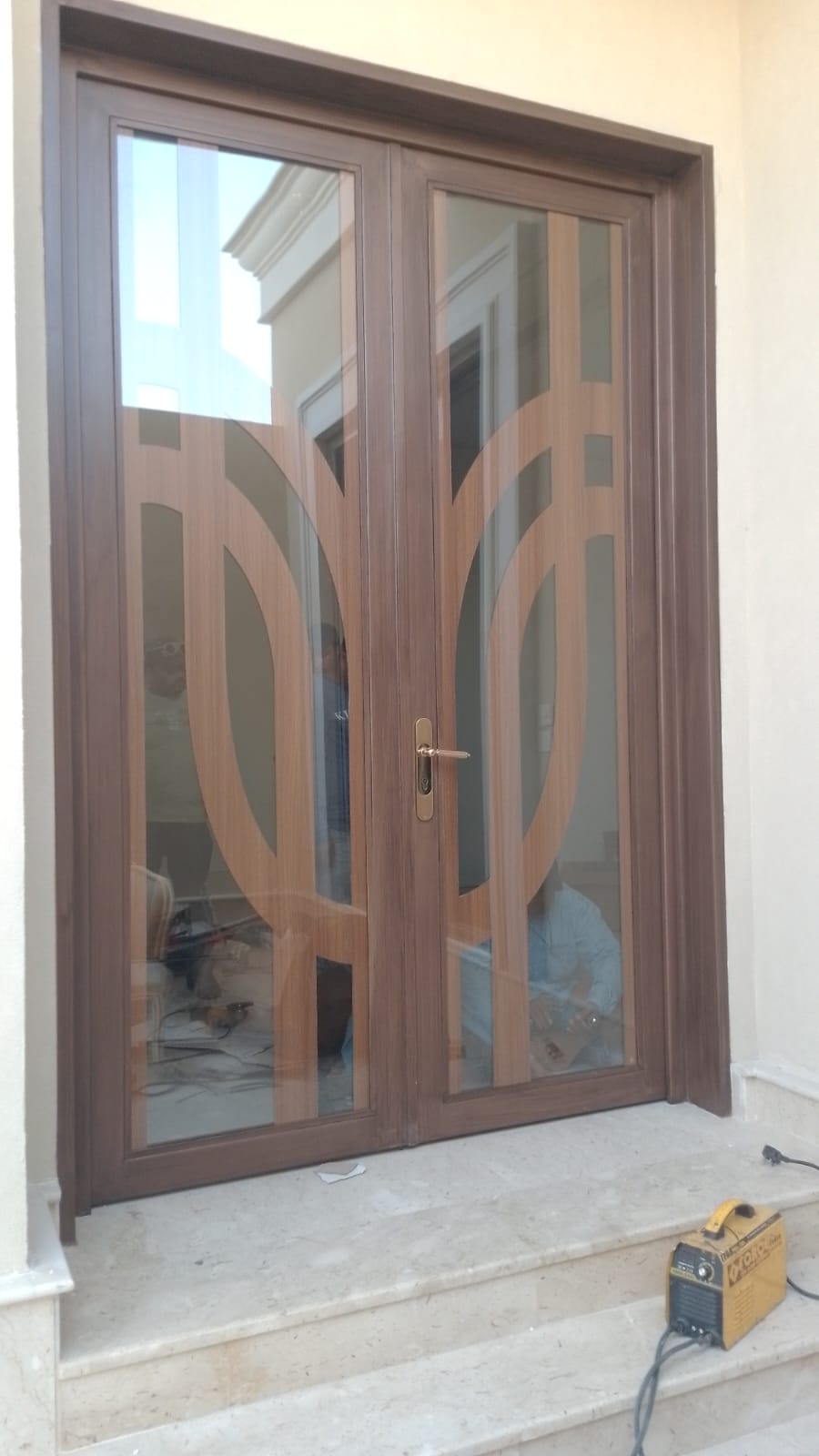 Steel and glass double door with laser-cut arch pattern overlay